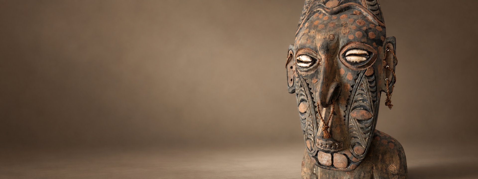 Carved Papua New Guinean mask with cowrie shell eyes